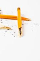 Gebrochener Bleistift mit Spänen auf weißem Hintergrund. vertikales Bild. foto
