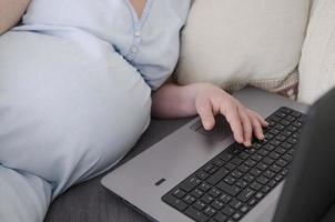 schwangere Frau, die am Laptop arbeitet foto