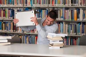 frustrierter Student wirft seinen Laptop foto