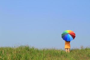 schöne Frau, die mehrfarbigen Regenschirm und blauen Himmel hält foto