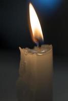 Kerze, die in einem schwarzen Hintergrund glüht foto