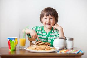 süßer kleiner kaukasischer Junge, der Pfannkuchen isst foto