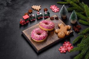 ein wunderschöner donut mit rosa glasur und farbigem streusel auf einem weihnachtstisch foto