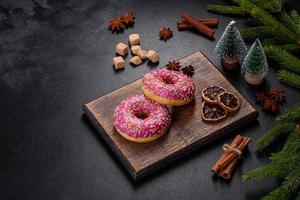 ein wunderschöner donut mit rosa glasur und farbigem streusel auf einem weihnachtstisch foto