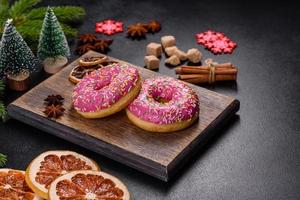 ein wunderschöner donut mit rosa glasur und farbigem streusel auf einem weihnachtstisch foto
