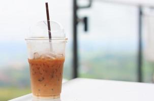 Eiskaffee mit Strohhalm im Plastikbecher mit Naturhintergrund foto