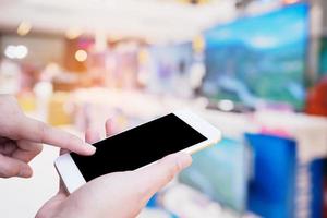 hand halten smartphone mit fernsehregal im elektronischen kaufhaus foto