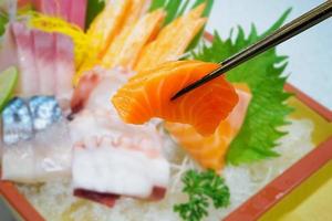 Lachs in Essstäbchen mit japanischem Sashimi auf Bootsteller foto