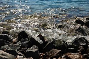 Große schwarze Steine an der Schwarzmeerküste mit Wellen, die gegen sie schlagen. Landschaft foto