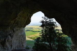 Blick von der weißen Felsenhöhle auf den Baum, den Weißdornbusch und die umliegende Landschaft. foto