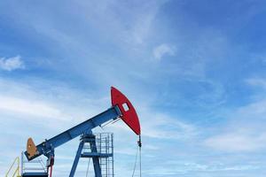 Öl Industrie. Ölbohrinseln. Ölpumpen auf einem Hintergrund des blauen Himmels mit Wolken. Platz kopieren. foto