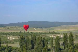 Heißluftballon, roter Ballon in Form eines fliegenden Herzens vor dem Hintergrund des weißen Felsens. foto