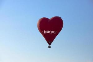 Heißluftballon, roter Ballon in Form eines fliegenden Herzens mit dem Text, ich liebe dich. foto