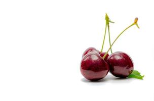 rote Kirsche mit Stiel und Blatt isoliert auf weißem Hintergrund. reife rote Süßkirsche. süße und saftige Bio-Kirsche. frisches obst für sommerdessert. Rohstoff für die Marmeladenindustrie. antioxidative Nahrung. foto