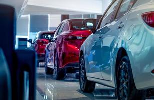 Rückansicht des neuen roten und weißen Luxusautos, das in einem modernen Ausstellungsraum geparkt ist. selektiver fokus auf weiß glänzendem auto. Autohaus-Konzept. Showroom-Interieur. Automobilindustrie zum Coronavirus-Krisenkonzept. foto