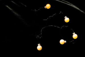 Dekorationslampe mit Licht auf schwarzer Wolle. Glühbirne warmes Licht auf schwarzem und glänzendem Friesstoff. foto