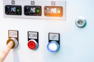 Die Hand des Ingenieurs drückt den grünen Knopf, um die Temperaturregelungsmaschine zu öffnen. Temperaturkontrollschrank enthält eine digitale Bildschirmanzeige für die Temperaturanzeige. Wärmeregelung in Industriefabriken. foto