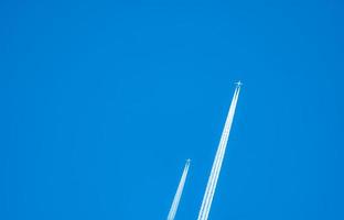 zwei Flugzeuge mit weißen Kondensstreifen. Düsenflugzeug am klaren blauen Himmel mit Kondensstreifen. reise mit dem flugzeugkonzept. Abgasspuren von Flugzeugmotoren. Flugzeuge mit weißen Streifen. foto