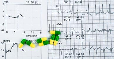 ekg- oder ekg-elektrokardiogramm-berichtspapier. est-belastungstestergebnis und grün-gelbe kapselpillen. Paketwerbung für Herzuntersuchungen im Senioren- oder Seniorenkonzept. foto