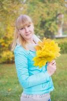 blondes Mädchen mit gelbem Ahornblatt foto