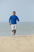 gesunder junger Mann, der am Strand joggt foto