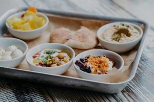 Lebensmittel- und Ernährungskonzept. traditionelles israelisches gericht zum abendessen. Tablett mit köstlichem Hummus, Rüben mit Gewürzen, Tomatenkern, Fladenbrot, Ziegenkäse für Sie serviert