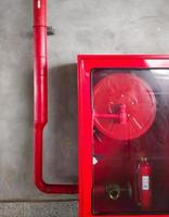 der rote Notfallschrank mit der Feuerwehrschlauchtrommel und dem Feuerlöscher. foto
