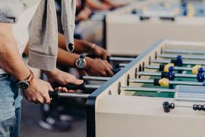 menschen, lebensstil, glücksspiel und erholungskonzept. aktiver männlicher spieler genießt die freizeit, während er zusammen tischfußball spielt. Leute haben Kicker-Match foto