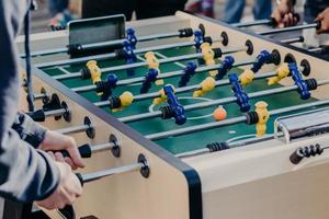 männliche Freunde verbringen unvergessliche Stunden miteinander, spielen Kicker oder Kricker, haben Spaß, wollen den Sieg erringen. Schließen Sie herauf Bild von bunten Plastikspielern foto