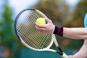 Nahaufnahme der Hände des professionellen männlichen Tennisspielers, der Schläger hält