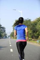 Fit Sportfrau läuft auf Asphaltstraße foto