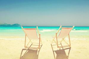 Entspannen Sie sich am tropischen Strand in der Sonne auf Liegestühlen. foto