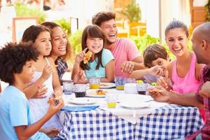 multiethnische Familien, die in einem Restaurant im Freien essen