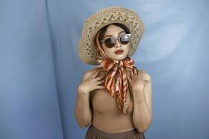 Reisekonzept einer jungen asiatischen Retro-Frau, die durch einen blauen Hintergrund isoliert ist foto