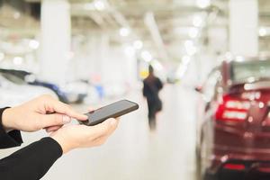 Hand benutzt Telefon über verschwommenes Foto einer Frau, die gefährlich auf einem Parkplatz läuft