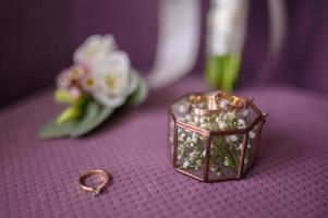 Eheringe und ein Brautstrauß auf einem lila Stuhl. foto