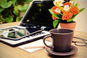 Laptop und Tasse Kaffee mit Blume auf dem Schreibtisch foto