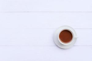 Draufsichtbild eines heißen Latte-Kaffees in einer weißen Tasse auf einem weißen Holztisch mit Kopienraum foto