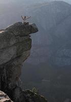 Junger Mann hebt seine Arme am Rand steiler Klippen im Yosemite-Nationalpark foto