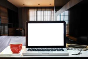 Vorderansicht von Tasse und Laptop, Smartphone und Tablet auf dem Tisch im Büro und Hintergrund im Café foto