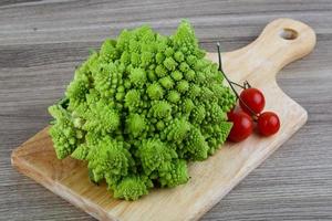 Romanesco-Kohl auf Holzplatte und Holzhintergrund foto