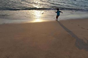Junge läuft auf einem Hawaii-Strand.