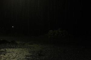 Regen in der Nacht. dunkle Hintergrundaufnahme von fallendem Regen foto