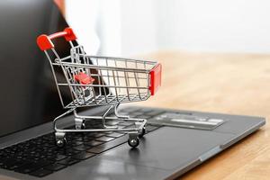 Einkaufswagen und Kreditkarte auf Laptop im Büro. Konzept-Shopping online foto