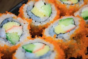 Sushi-Rolle, Reihe von kalifornischen Maki-Rollen-Sushi mit Kaviar auf schwarzem Teller foto