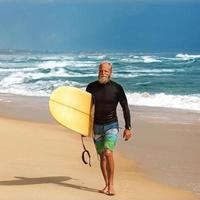 Surfer am Meer steht mit einem Surfbrett foto