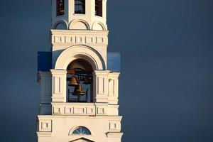 eine alte orthodoxe Kirche am Ufer des Flusses. Sonnenuntergangssonne und schwarze Wolken. foto