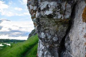 ein Felsen in der Nähe des Flusses und des Dorfes vor dem Hintergrund des Sonnenuntergangshimmels. foto