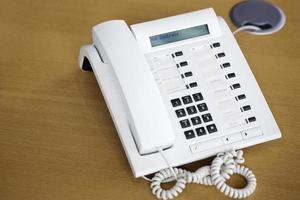 weißes Telefon auf hölzernem Schreibtisch