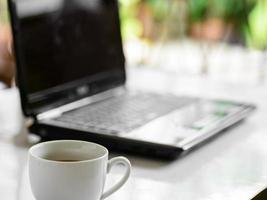 Kaffeetasse und Laptop für Unternehmen, selektiver Fokus auf Kaffee. foto